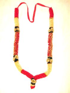 a beaded necklace with gold and red beads on a white background, hanging from a string