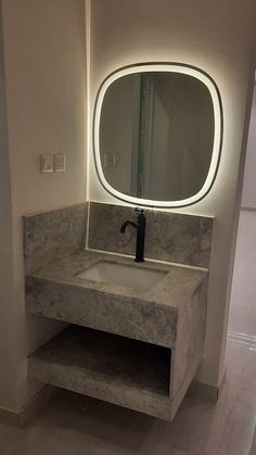 a bathroom sink with a round mirror above it