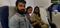 three people are sitting on an airplane and smiling