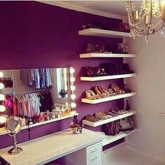 a room with a vanity, mirror and lights on the wall next to shelves filled with shoes