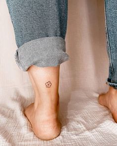 a person's foot with a small flower tattoo on their left ankle and right leg