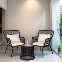 two chairs sitting next to each other in front of a glass wall with a candle on it