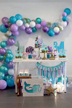 an under the sea themed party with balloons and mermaid cake, cupcakes and decorations