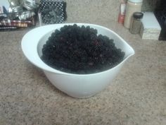 a white bowl filled with blackberries sitting on top of a counter next to other items