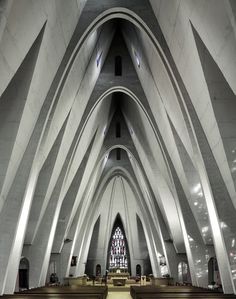 the interior of a large cathedral with pews and stained glass windows on both sides