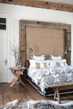 a bed sitting in a bedroom next to a wooden table and white walls with a mirror on the wall