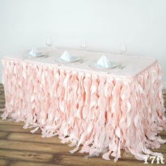 the table is covered with pink ruffles and silver place settings