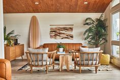 a living room filled with furniture and a surfboard hanging on the wall above it