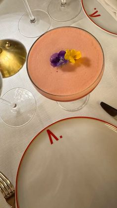 the table is set with two plates and three glasses, one has a purple flower on it