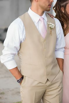 a man in a suit and tie standing next to a woman wearing a pink dress