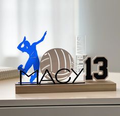 an acrylic figure stands next to the word mac on top of a desk