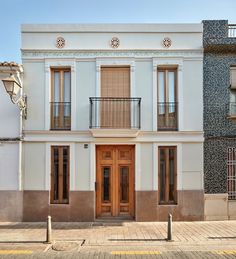 an old white building with two balconies on the second floor and a wooden door