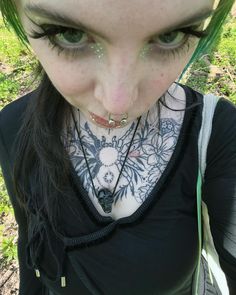 a woman with green hair and piercings on her neck