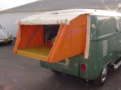 an orange and green camper van parked in a parking lot next to a building