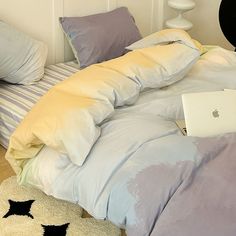 an apple laptop computer sitting on top of a bed covered in blue and yellow sheets