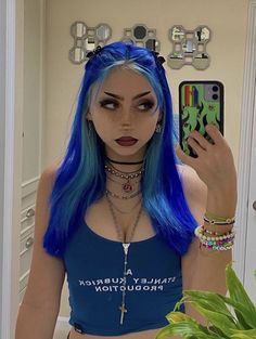 a woman with blue hair is taking a selfie in front of a mirror and holding a cell phone