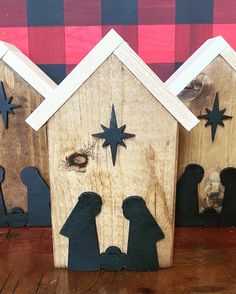 three wooden nativity houses with black silhouettes and star cutouts on the sides