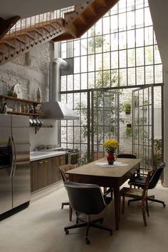 an open kitchen and dining area with stairs leading up to the second floor that has glass doors on both sides