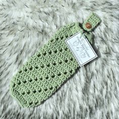 a crocheted bottle cover with a tag attached to it on a furry surface