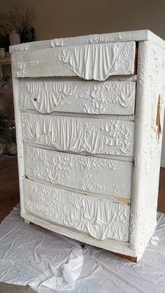 a white painted dresser sitting on top of a bed