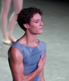 a man with his hands on his chest standing in front of a ballerina's feet