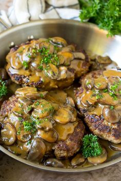 some meat patties covered in mushroom gravy and garnished with parsley