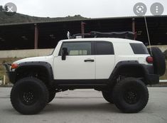 a white truck with black tires parked in front of a building