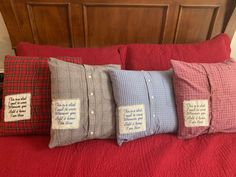 four pillows are sitting on top of a bed with red sheets and plaid pillow cases