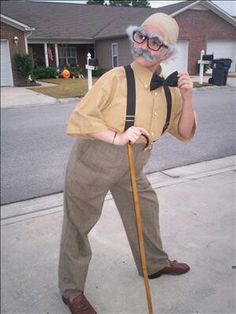 an old man with glasses and a cane is standing on the sidewalk in front of a house