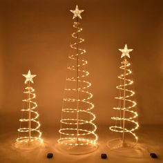 three christmas trees with lights on them in the shape of spirals and star shapes