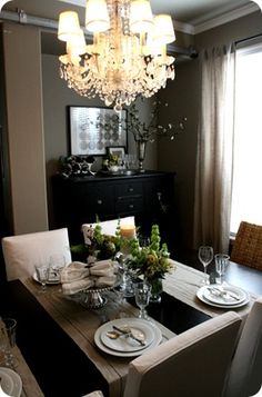 the dining room table is set with place settings for four people and has a chandelier