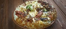 a pizza sitting on top of a wooden table covered in cheese and toppings with broccoli