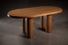 a wooden table sitting on top of a cement floor next to a black wall in an empty room