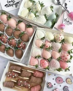 two boxes filled with chocolate covered strawberries next to other treats and desserts on a table