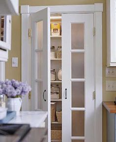 an open pantry door in a kitchen next to a counter top with baskets on it