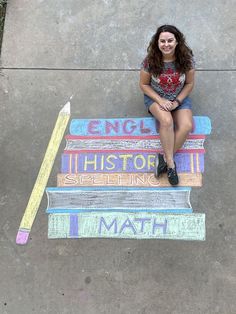 a woman sitting on top of a bench next to a stack of books and a pencil