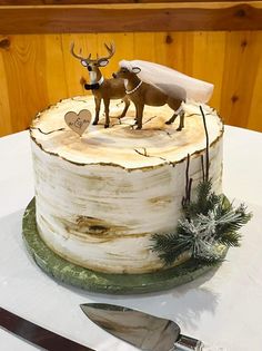 a cake decorated with two deer on top of a tree stump