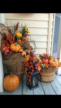 two baskets filled with pumpkins and other autumn decorations on a porch next to a window