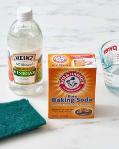 ingredients for baking soda sitting on a counter next to a bottle of vinegar and cloth