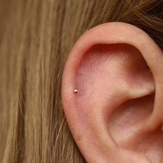 a close up of a person's ear with a tiny piercing