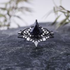 a black diamond ring sitting on top of a stone slab with white diamonds around it