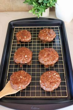 four hamburger patties on a baking sheet with a spatula