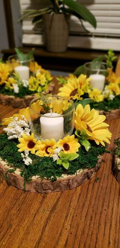 sunflowers and greenery are arranged around a candle holder on a wooden table