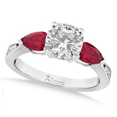 a white gold ring with two red pear shaped diamonds on the band and a diamond set in