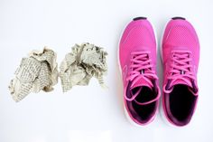 a pair of pink tennis shoes next to crumpled newspaper on a white background with space for text