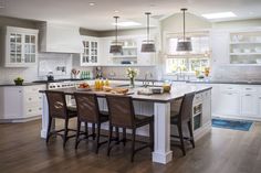 a large kitchen with white cabinets and wooden floors