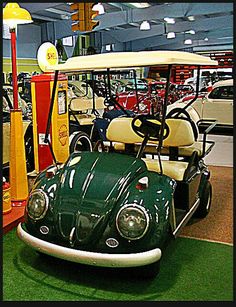 a green golf cart parked in front of a gas pump at a car dealership