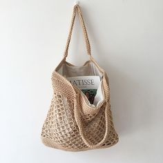 a crocheted bag hanging on the wall with a magazine in it's pocket