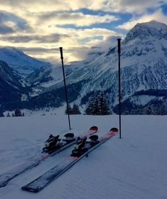 two skis are sitting in the snow with mountains in the background