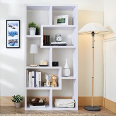 a white book shelf with books and other items on top of it in a living room